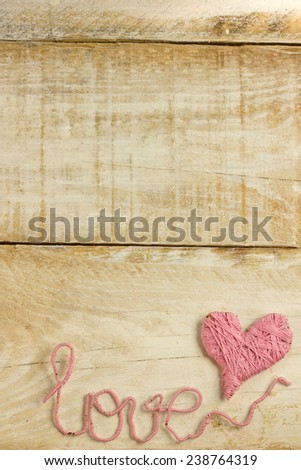 Pink clew in shape of heart and word "love"on vintage wooden background