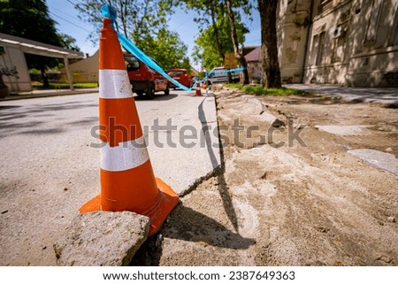 Orange traffic cone with white fluorescent stripes is on the road for pointing to alert and divert traffic, sign with boundary are symbols of caution.