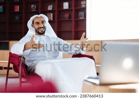 handsome man with dish dasha working in his business office of Dubai. Portraits of a successful businessman in traditional emirates white dress. Concept about middle eastern cultures. Royalty-Free Stock Photo #2387660413