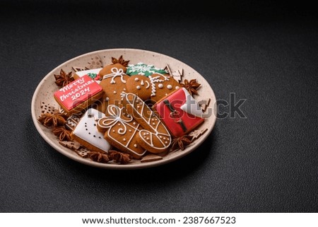 Beautiful Christmas gingerbread cookies of different colors on a ceramic plate on a dark concrete table