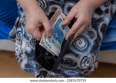 An old lady takes out money from her wallet, Polish cash Royalty-Free Stock Photo #2387670729