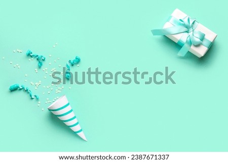 Frame made of party cone with serpentine, confetti and gift on green background