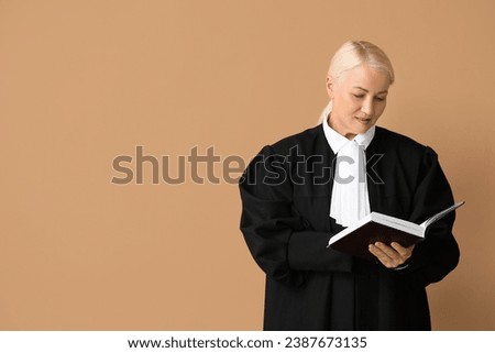 Mature female judge with book on brown background