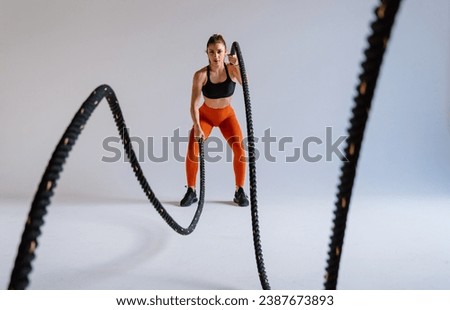 Young female athlete training in a gym using sport equipment. Fit woman working out . Concept about fitness, wellness and sport preparation. Royalty-Free Stock Photo #2387673893