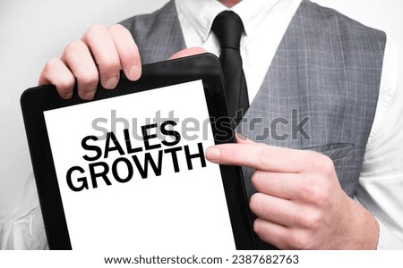 Businessman showing business concept on tablet standing in office SALES GROWTH