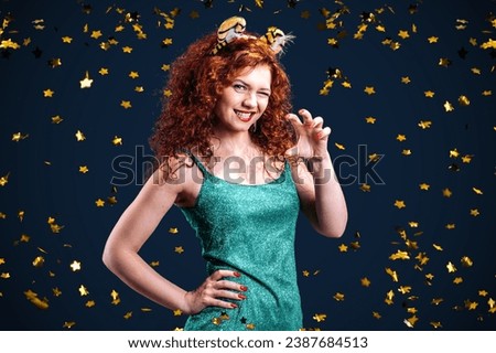 A woman in a green dress with tiger ears stands under flying confetti. The tigress girl smiles and laughs. New Year of the tiger. Celebration or party in honor of 2034. Birthday