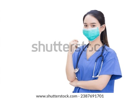 Professional young Asian woman doctor wears medical clothing and face mask to protect Coronavirus disease 2019 Covid 19 outbreak while shows her hand to suggest something on white background.  Royalty-Free Stock Photo #2387691701