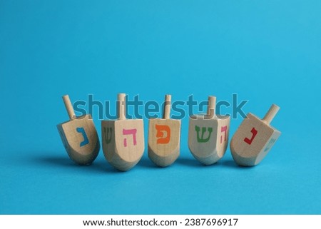 Wooden dreidels on light blue background. Traditional Hanukkah game