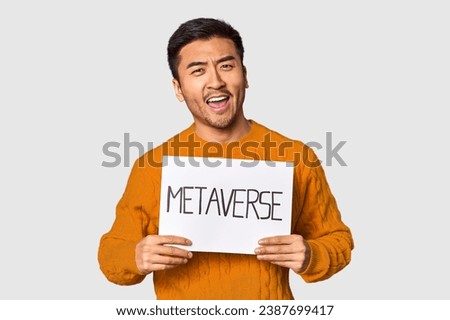 Young Chinese man showcasing "metaverse" sign in studio background