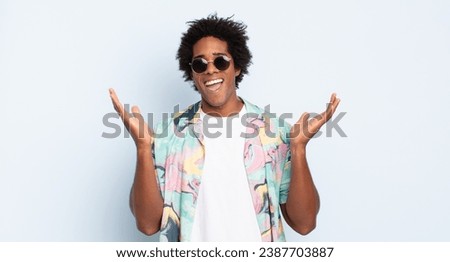 young black afro man feeling happy, excited, surprised or shocked, smiling and astonished at something unbelievable Royalty-Free Stock Photo #2387703887