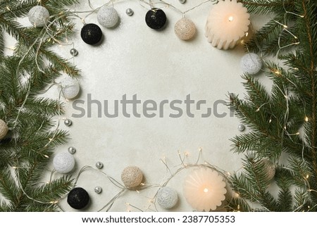 Christmas tree branches, candles, garland and balls on light background, space for text