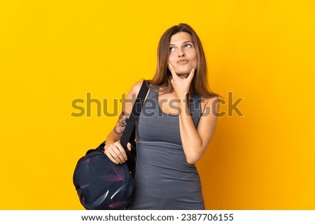 Slovak sport woman with sport bag isolated on yellow background having doubts