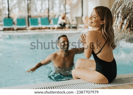 Handsome young couple having fun in the indoor swimming pool Royalty-Free Stock Photo #2387707979