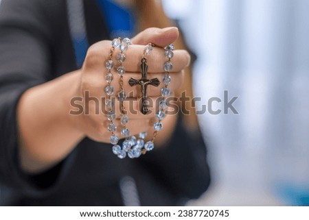 A young girl holds a rosary with a cross in her hand, prays