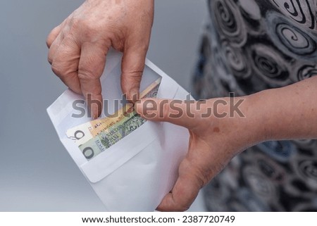 An elderly lady hides the money, Polish zloty, in an envelope