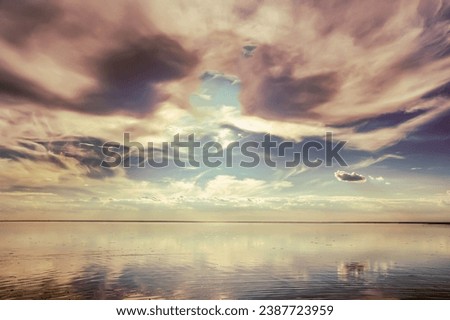 The colorful sky with clouds is reflected on the surface of the water.  Smooth water surface with reflection.    The sky over the salt lake.