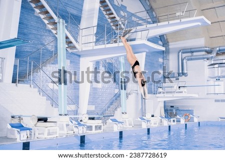 girl doing extreme tricks jumping into water, spring-board diving championships Royalty-Free Stock Photo #2387728619