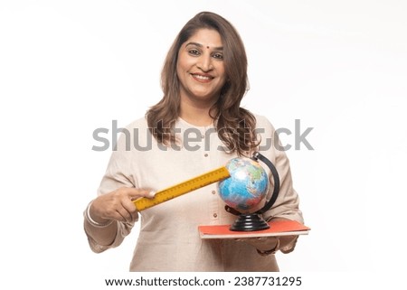 Portrait of Indian confident woman pointing through wooden scale to world globe map against on white background teacher concept.
