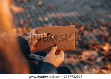 Female hands put the letter in the craft envelope. Woman holding a craft envelope Royalty-Free Stock Photo #2387732913