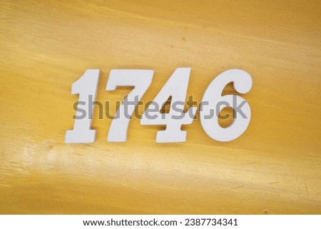 The golden yellow painted wood panel for the background, number 1746, is made from white painted wood. Royalty-Free Stock Photo #2387734341