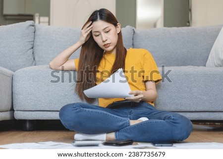 young woman using calculator calculating monthly expense from invoice receipt for manage personal finance and mortgage loan on the floor at home.