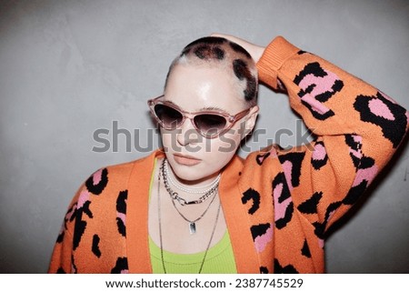 Portrait of confident young woman with cheetah print hair art wearing sunglasses in studio Royalty-Free Stock Photo #2387745529