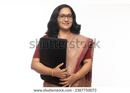 Portrait of Indian female teacher looking in front of the camera. wearing in saree and sunglasses  while holding folder. Confident traditional Indian woman against white background