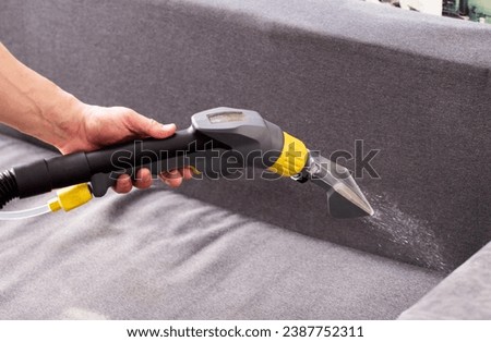 Applying a special cleaning solution to clean stains and dirt on upholstery of upholstered furniture. The first stage of dry cleaning. Royalty-Free Stock Photo #2387752311