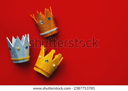 Three crowns of the three wise men with copy space over red background. Concept for Reyes Magos day. Three Wise Men concept Royalty-Free Stock Photo #2387753781