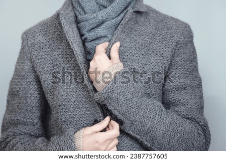 Close-up of a woman in a gray knitted jacket and blue scarf. Winter, autumn warm woolen clothes. Royalty-Free Stock Photo #2387757605