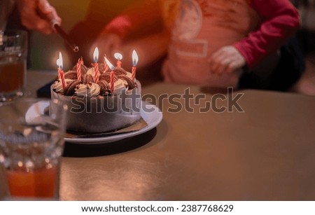Cropped image of little asian boy blowing candles while three generation family celebrating her birthday at home