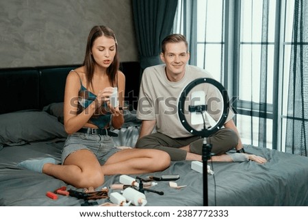 Young woman making beauty and cosmetic tutorial video content for social media using her boyfriend as model and light ring. Beauty blogger showing how to beauty care to audience or follower. Unveiling Royalty-Free Stock Photo #2387772333