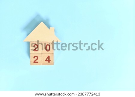 Year 2024 house or home ownership and real estate property investment concept. Wooden blocks on blue background with icon.