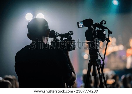 Professional digital video camera technician. Videographer with equipment at event. Royalty-Free Stock Photo #2387774239