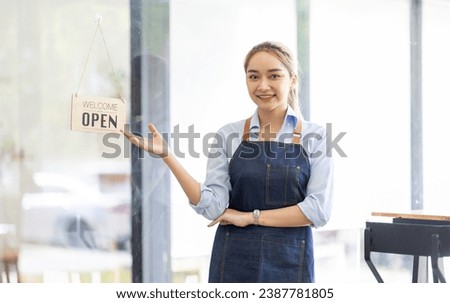 Happy SME business barista cafe owner Asian woman waitress apron and staning at the door with a sign Open waiting for customers , cafes and restaurants entrepreneur Small business concept.