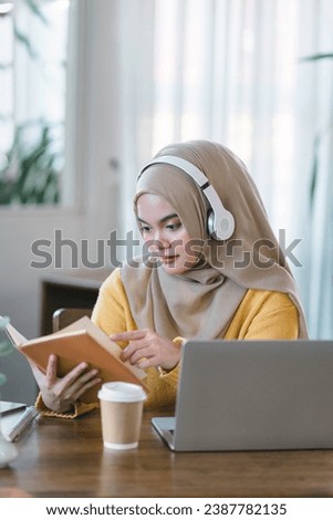 An Asian Muslim university student relaxes while reading a book at home