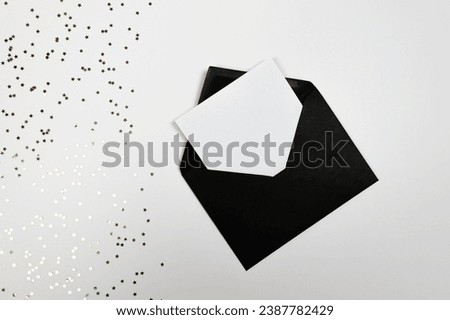 Christmas composition, black envelope, gold stars confetti on white background. Christmas, New Year, winter concept. Top view, flat lay, copy space. 