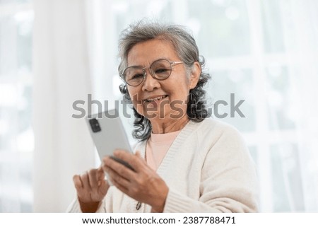 Happiness beautiful elderly asian woman with white hairs sitting on sofa using mobile phone and social media smile in cozy living room at home,Senior Wellness lifestyle at home concept Royalty-Free Stock Photo #2387788471