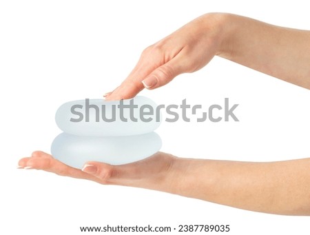 Hand pressing soft breast implants in hand isolated on white background with clipping path. Royalty-Free Stock Photo #2387789035
