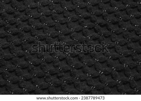 Acrylic textile texture background: black woolen fabric material, sheep wool clothing, dark soft warm clothes. Knitted tissue of pullover, knitwear sweater, lurex, cross pattern