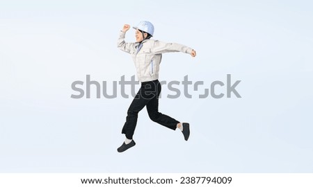 Asian woman wearing work clothes jumping energetically. Engineer. Industrial worker. Wide angle visual for banners or advertisements.