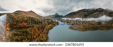 Harmony of Autumn: Aerial Tapestry Over Lanuza Reservoir and Village, with Foratata Peak Gracing the Horizon, Amidst the Vibrant Kaleidoscope of Fall Colors in the Picturesque Aragonese Pyrenees
