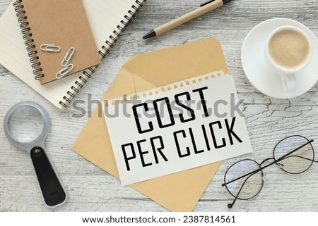 COST PER CLICK CONCEPT white paper clips on a notepad. paper with text on the envelope. magnifying glass and glasses