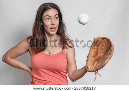 Woman in pink T-shirt catches ball with a baseball glove. Surprised facial expression.