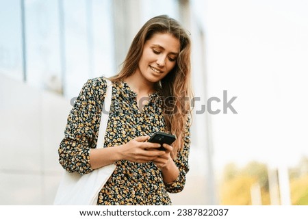 Close up photo of young woman using her smartphone outdoors in city