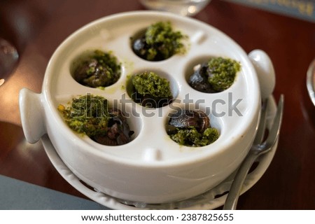 Starter dish in traditional restaurants on Burgundy, snails cooked with butter, garlic and herbs, France served on white porcelain plate