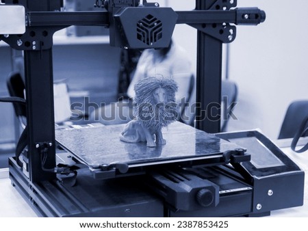 Model of toy lion printed on 3D printer from melted plastic blue color on desktop of 3D printer. Concept 3D printer, 3D printing, modeling prototyping three dimensional object. Innovative production