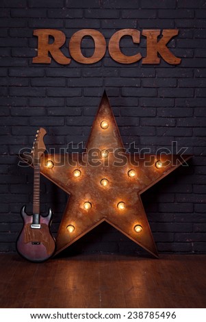 Electric Guitar And Iron Star Leaning On Brick Wall