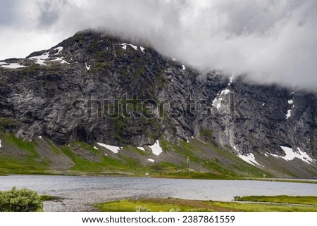 Epic mountains of Norway Cascading into the Fjords with fresh summertime green as Glaciers melt at the summit