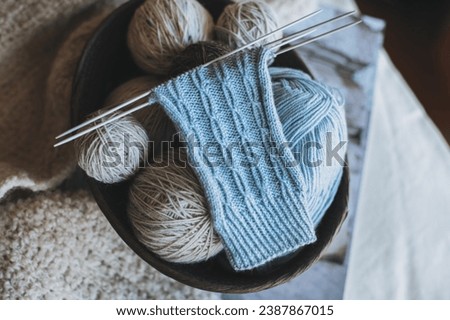 Hand knitted socks with needles and yarn ball in a basket. Concept for handmade and hygge slow life.